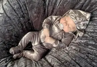 Bebê vestindo um macacão de veludo brilhante dormindo pacificamente