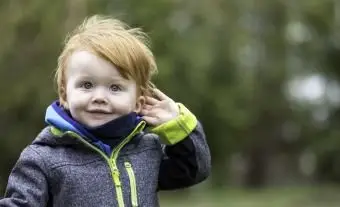 Garoto ruivo ouvindo sons da natureza ao ar livre