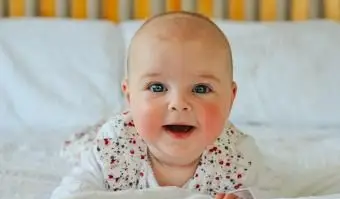 תינוק מחייך שוכב על בטנה