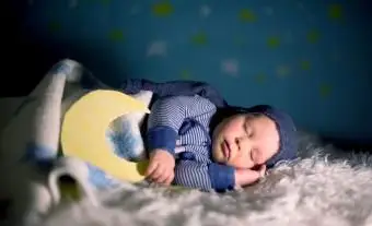 Kleines Baby mit süßem Teddybär und Mond