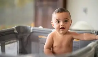 dieťa v ohrádke pri pohľade na fotoaparát