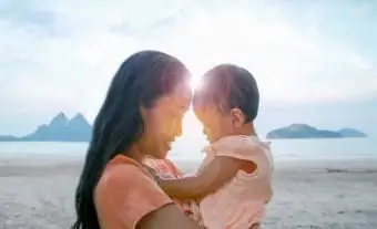 Madre e hija en la playa contra el cielo