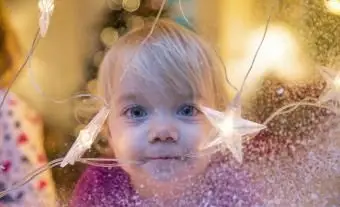 Niña mirando por la ventana con estrella de Navidad