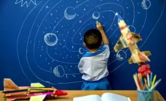 描かれた空間でロケットに手を伸ばす小さな男の子