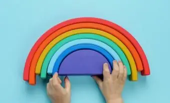 Ręce dzieci bawiące się drewnianą zabawką tęczy