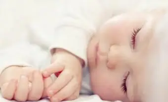 Piękne śpiące dziecko na białym łóżku