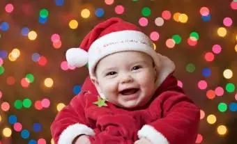 Buźka dziewczynka w stroju Świętego Mikołaja na świątecznym podświetlanym kolorowym tle