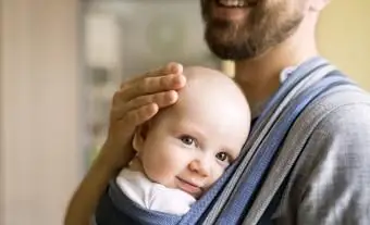 Padre con figlio in fascia a casa
