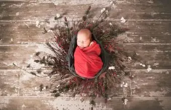 Portret noworodka owiniętego w świąteczną gazę i szydełkową chusteczkę