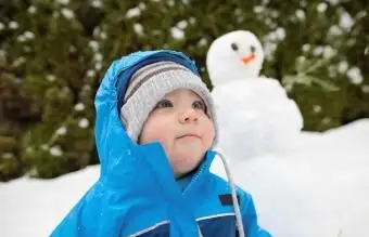 chłopiec na zewnątrz z bałwanem w tle