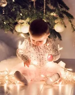 Mała dziewczynka w spódniczce tutu siedzi wokół choinki