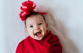 Dziewczynka z czerwoną wstążką na głowie owinięta czerwonym kocem