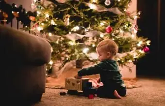 chłopiec bawi się zabawkową ciężarówką przy choince w domu