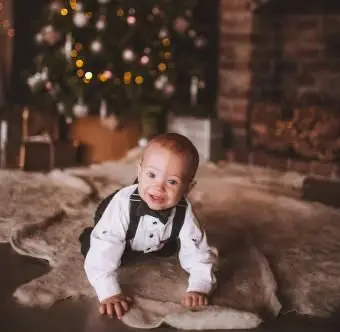 Mały chłopiec czołgający się na podłodze na tle choinki w domu