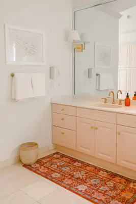 pink vanity with a red rug in front of it and white towels hanging by it