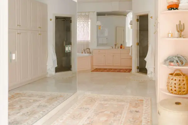 bathroom with pink vanity and pink rug in front of a full length mirror
