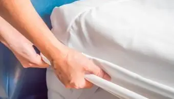 Kobieta kładąca narzutę na pościel na łóżku