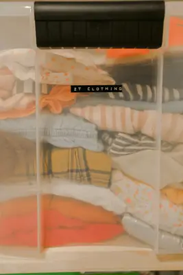 clear bin with a black label on it that says 2T clothing