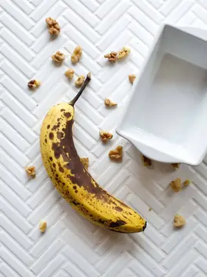 a ripe banana and a loaf dish with walnuts around it