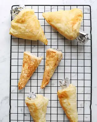 carrot-shaped pastries with foil on wire rack