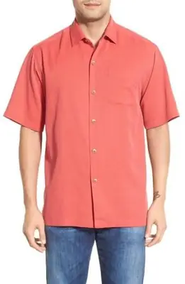 Homme portant un polo et tenant un appareil photo à la plage