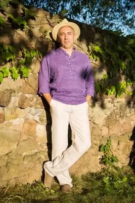 L'homme en chemise de lin et chapeau de paille se tient près du mur de pierre