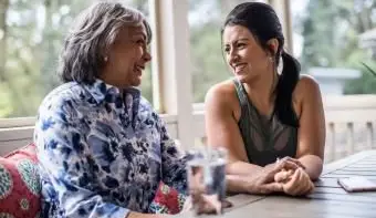 Donna anziana e figlia adulta che ridono sotto il portico