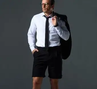 איש במכנסיים קצרים מחזיק מעיל על הכתף