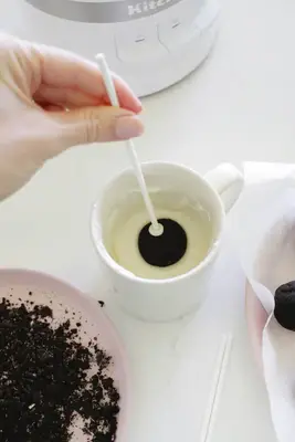 Dipping oreo cake pop balls into melted chocolate