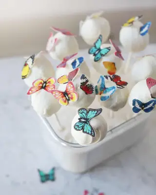 white cake pops with fake butterflies on top
