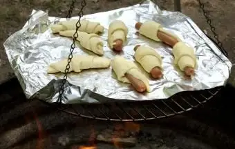 Porcs dans une couverture faisant cuire au-dessus d'un feu de camp