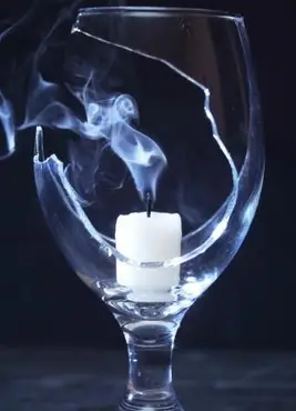 Candela spenta con fumo all'interno di un bicchiere di vino rotto