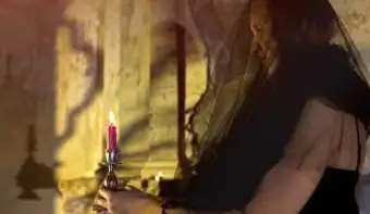 古代の祭壇のそばに立っているろうそくを持つ女性