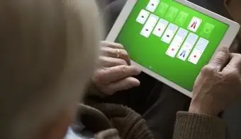 デジタルタブレットでソリティアをプレイする年配の男性