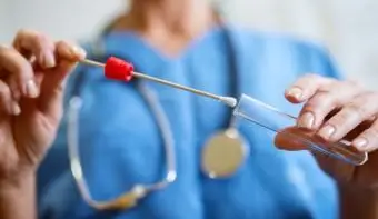 Infirmière tenant un coton-tige buccal et un tube à essai