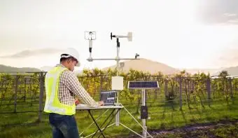 אגרונום משתמש במחשב כדי לאסוף נתונים באמצעות מכשיר מטאורולוגי למדידת מהירות הרוח