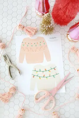 Paper Christmas sweaters about to be cut out with scissors