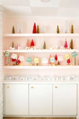 Paper Christmas sweaters strung on a garland with Christmas tree shelf decor