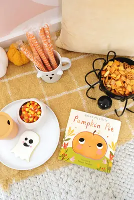 book with a pumpkin on it sitting by snacks on a blanket
