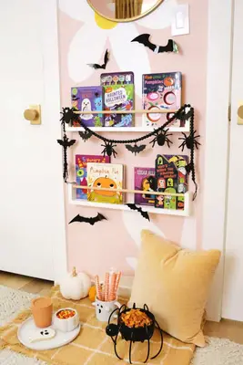 halloween decorated bookshelf with snacks, a blanket, and pillow underneath