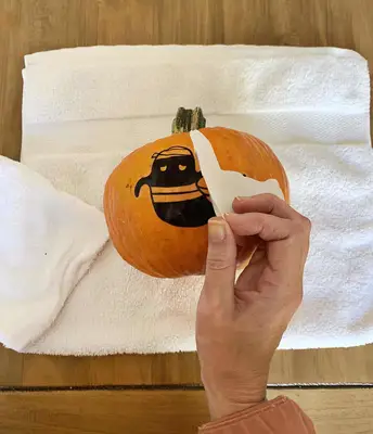 Peeling the tattoo paper off the pumpkin