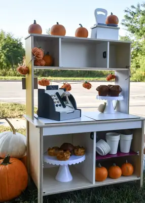 Inside of pumpkin stand, can see the treats, back of cash register, cups and pumpkins.