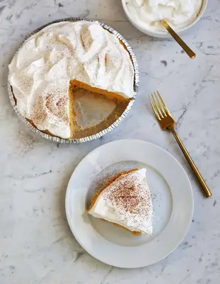 no bake pumpkin pie with a piece cut out an don a white plate with a gold fork next to it