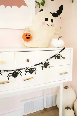wooden spider garland strung across a console table decorated with pumpkins
