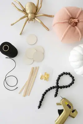 wooden sticks, wooden circles, glue gun, black beads, and twine laying on a table