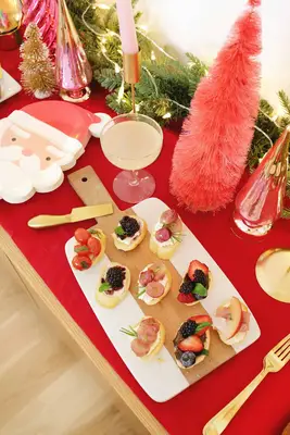 5 different crostinis on a marble serving board with Christmas decorations around it