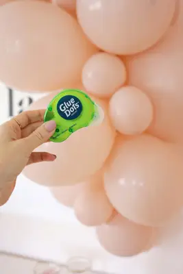 adding pink balloons to garland over table