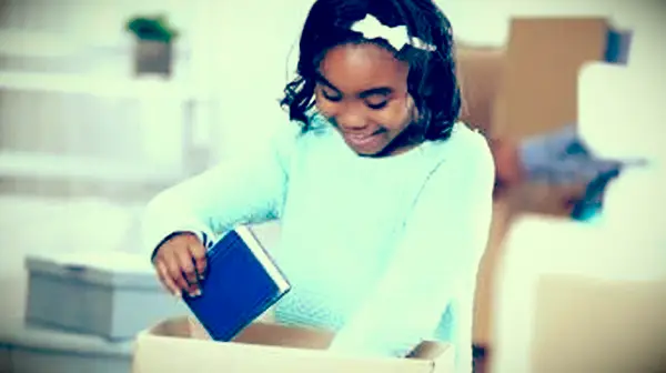 dievča balí knihy do kartónovej krabice