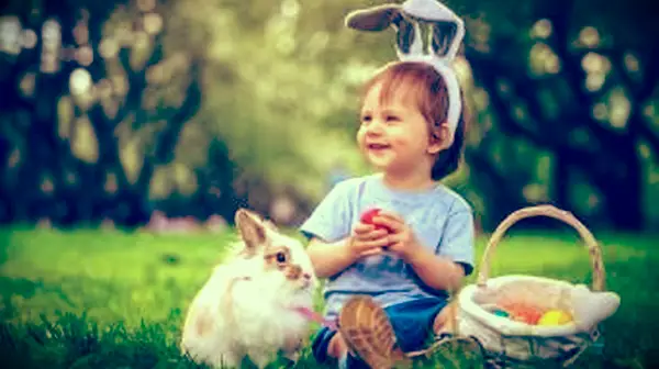 Chlapec sa hrá so zajačikom a veľkonočnými vajíčkami