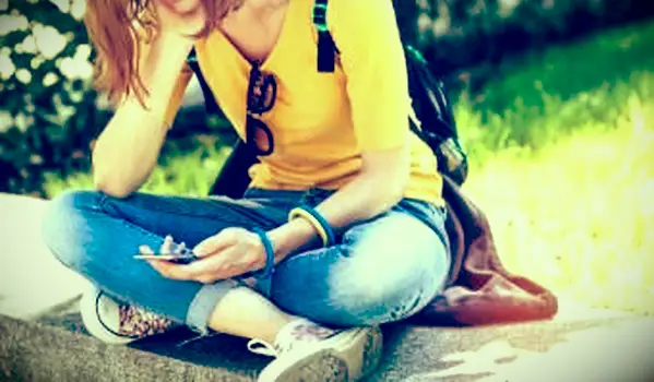 公園で一人で座って、彼女の電話で読んでいる悲しい10代の少女